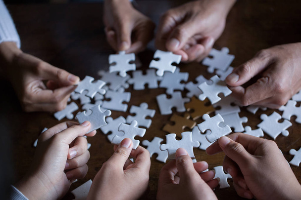 Hände von verschiedenen Leuten, die Puzzle zusammenbauen, Jugendteam setzt Teile zusammen, um das richtige Spiel zu finden, Unterstützung bei der Teamarbeit, um ein gemeinsames Lösungskonzept zu finden, Nahsicht von oben - Foto, Bild