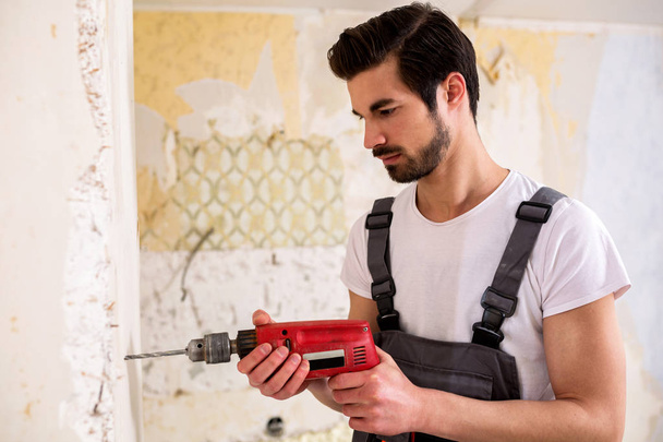 Bearded guy drilling a hole with standard electric drill - Foto, Imagen