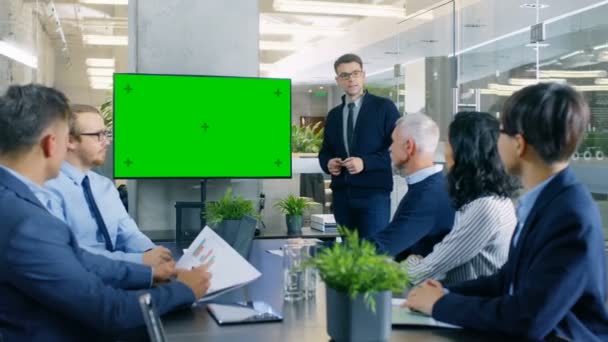 Zakenman geeft verslag / presentatie aan zijn collega's, wijzend op de groene Chroma Key scherm muur Tv. - Video