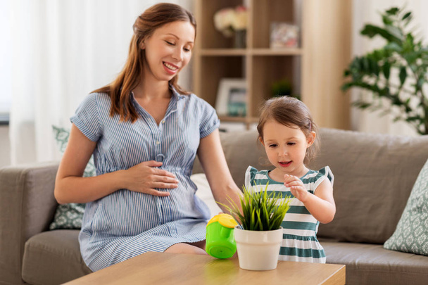 pregnant mother and daughter with home plant - Foto, immagini