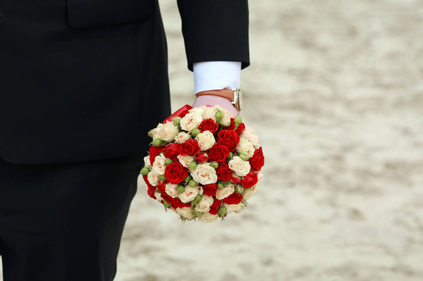 Luksusowy bukiet czerwonych i białych kwiatów w ręku stajennych. dzień ślubu - Zdjęcie, obraz