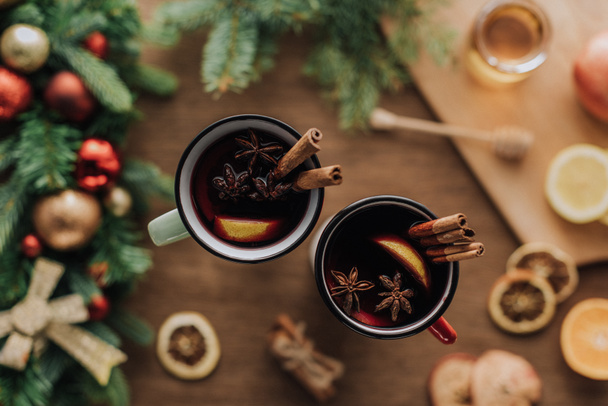 top view of cups of mulled wine with cinnamon sticks on wooden tabletop, christmas concept - Photo, Image