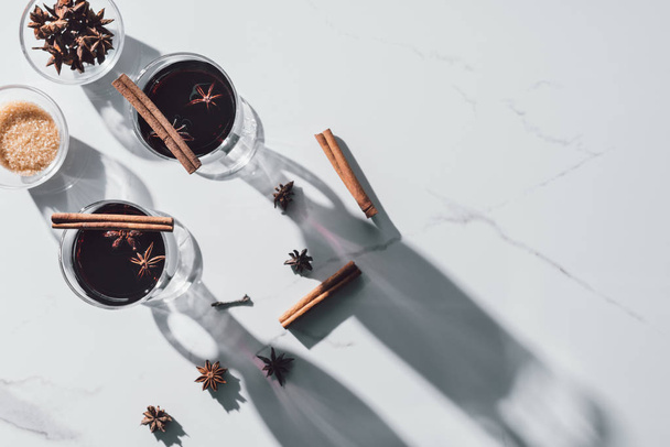 top view of glasses of mulled wine and carnation on white tabletop - Foto, Imagen