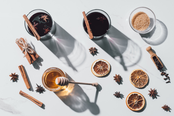 top view of glasses of mulled wine, honey and brown sugar on white tabletop - Photo, Image
