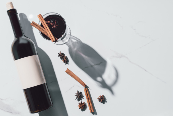 το Top view mulled κρασί σε ποτήρι και κρασί μπουκάλι σε λευκά επιτραπέζια - Φωτογραφία, εικόνα