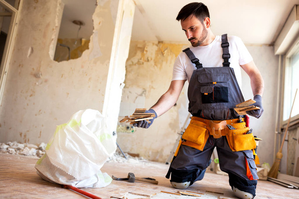 Handsome man doing manual labor removing old parquet tiles and flooring - 写真・画像