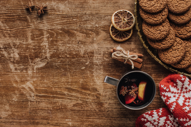 top view of mulled wine in cup, mittens and cookies on wooden tabletop, christmas concept - Photo, Image
