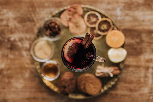 elevated view of mulled wine in cup and cookies on round tray on wooden table - Foto, Imagem
