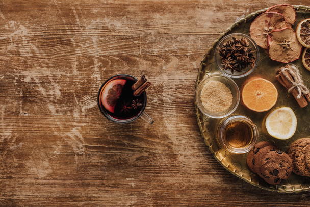 top view of mulled wine in cup and round tray with sweets on wooden table - Foto, afbeelding