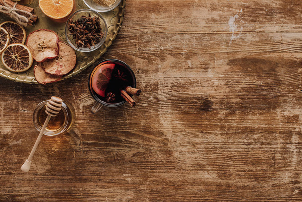 top view of cup of mulled wine and honey on wooden table - Foto, afbeelding