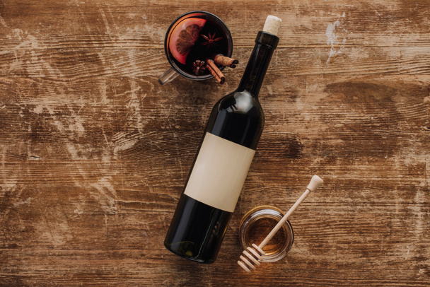 vista superior do vinho ruminado na xícara, garrafa de vinho e mel na mesa de madeira
 - Foto, Imagem