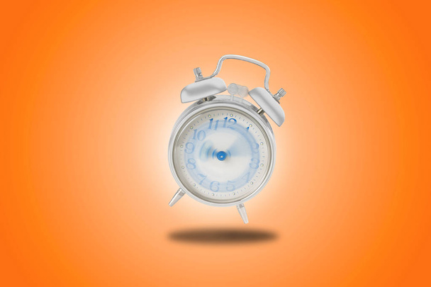 alarm clock, in orange background, that sounds madly with hands that turn non-stop - Photo, Image