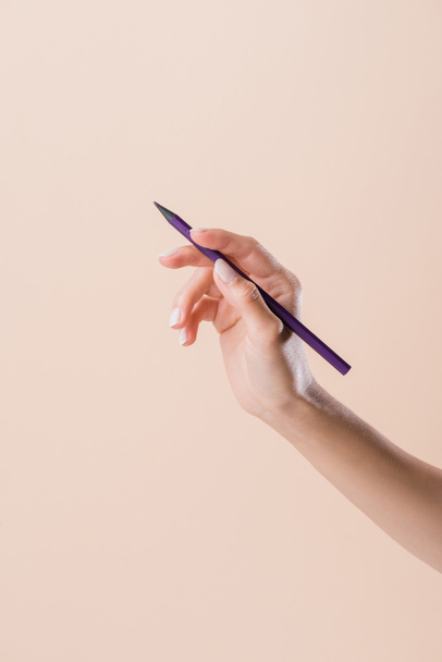 cropped shot of woman holding purple pencil isolated on beige - Фото, изображение