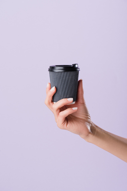 cropped shot of woman holding paper cup of coffee to go isolated on purple - 写真・画像