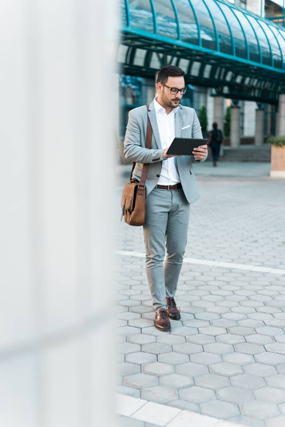 Young beautiful successful businessman holding tablet and walking through the city. - Foto, Imagem