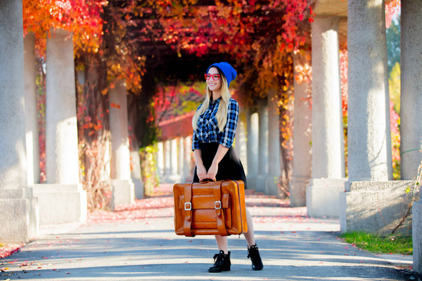 Joven chica blanca en sombrero y camisa con maleta en callejón de uva roja. Tiempo de temporada de otoño
  - Foto, imagen