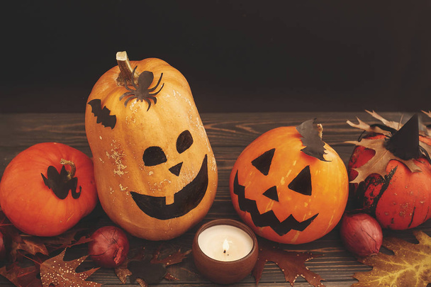 Happy Halloween concept. Pumpkins, candle light and autumn leaves on wooden background - Fotó, kép