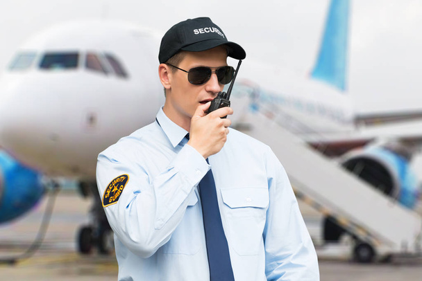 Portrait Of A Male Security Guard Talking On Walkie Talkie At An Airport - Foto, immagini