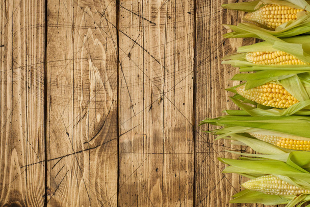 Fresh corn on cobs on rustic wooden table, closeup. - Foto, afbeelding