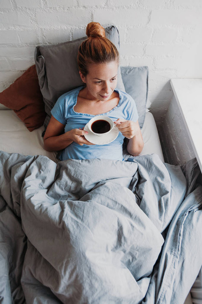 Woman drinking coffee in bed - Fotoğraf, Görsel