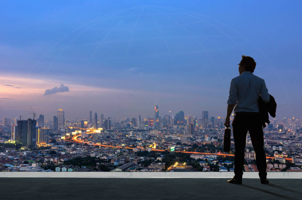 Concept vision, Young businessman wearing comfortable casual suit standing on top of building and looking through the modern buildings in the skyline. - Foto, Bild