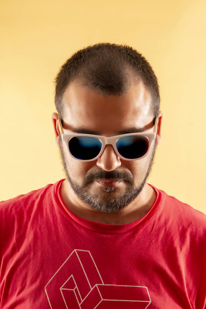 ο άνθρωπος με το κόκκινο πουκάμισο και λευκό γυαλιά ηλίου πάνω σε κίτρινο φόντο. - Φωτογραφία, εικόνα