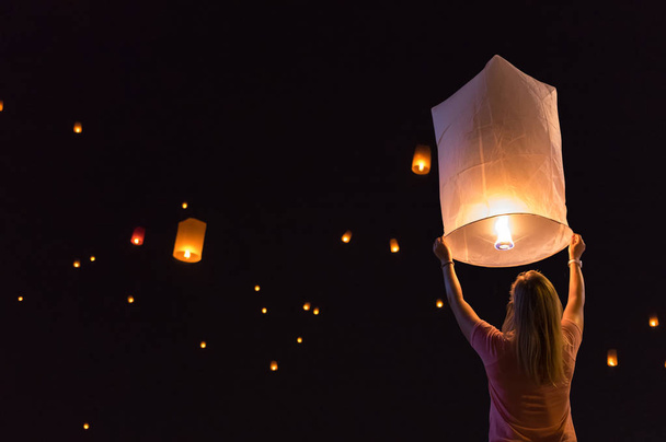 Woman releasing floating lanterns in the Loy Krathong festival or floating lanterns festival in Chiang Mai, Thailand. - Photo, image
