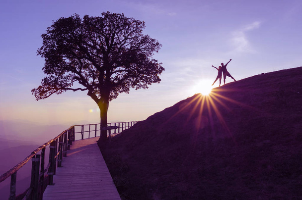 Coppia silhouette su collina e albero solitario, Il sole sta cadendo dietro con luci brillare Sulla cima della montagna (Doi Pui Co), attrazione turistica popolare a Mae Hong Son, Thailandia
. - Foto, immagini