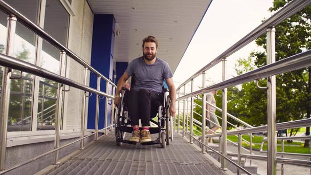 Ein behinderter Mann im Rollstuhl fährt den Hang hinunter - Foto, Bild