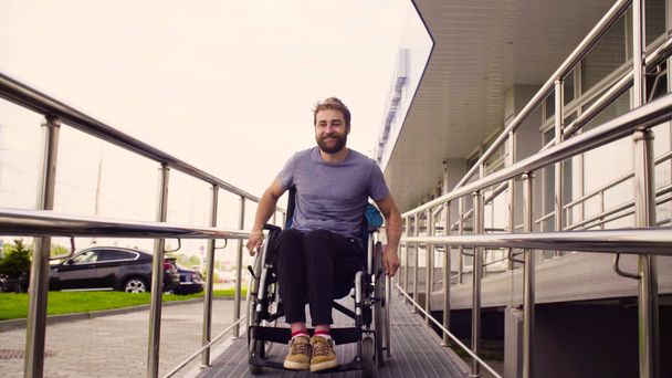 Een gehandicapte man in een rolstoel rijden naar beneden de helling - Foto, afbeelding