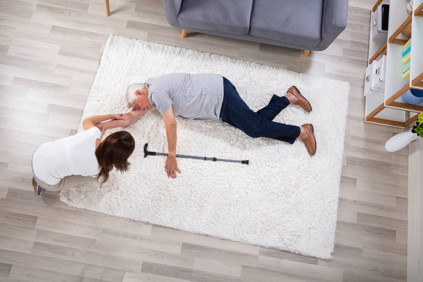 Woman Looking At Her Unconscious Father Lying On Carpet - Photo, Image