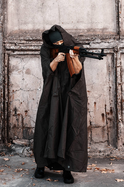 człowiek w płaszcz wojskowy i kominiarka celowania z karabinu maszynowego Kalashnikov Rpk - Zdjęcie, obraz