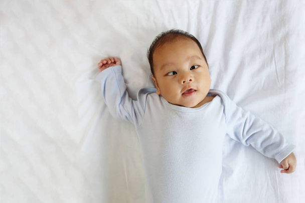 Азиатский младенец на кровати в фокусе внимания, концепция здорового роста
. - Фото, изображение
