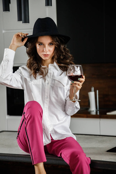 Fashion portrait of beauty brunette model wearing white shirt and pink pants. Young beautiful woman posing in luxury apartments interior - 写真・画像