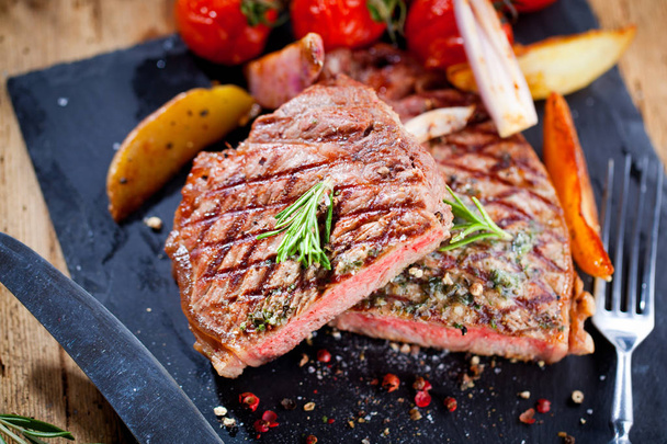 Нарезанный мясо барбекю стейк Striploin с ножом и вилкой резьба набор на черном камне шифер
 - Фото, изображение