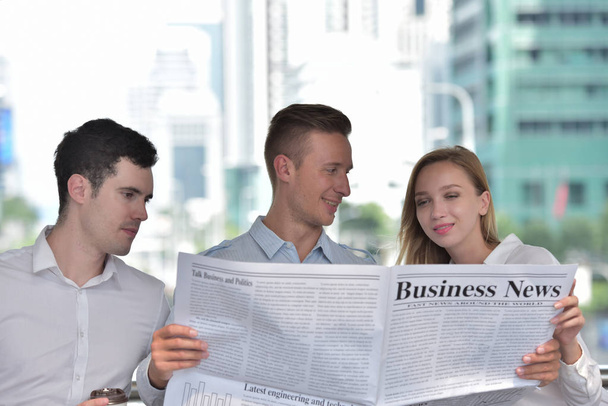 Трое бизнесменов читают газету и обсуждают в центре города
 - Фото, изображение