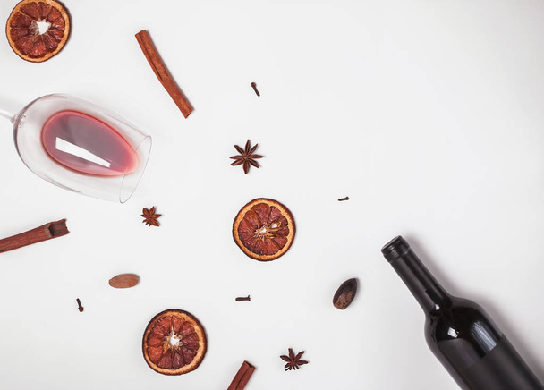 Şarap, şarap döktü ve beyaz zemin üzerine kuru baharat ile cam şişe - Fotoğraf, Görsel