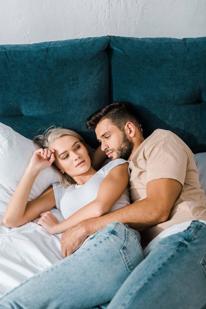 young handsome boyfriend cuddling girlfriend on bed in bedroom - Фото, зображення