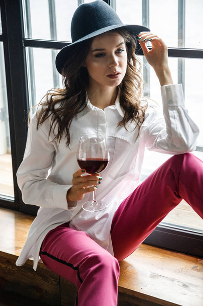 Fashion portrait of beauty brunette model wearing white shirt and pink pants. Young beautiful woman posing in luxury apartments interior - Фото, изображение