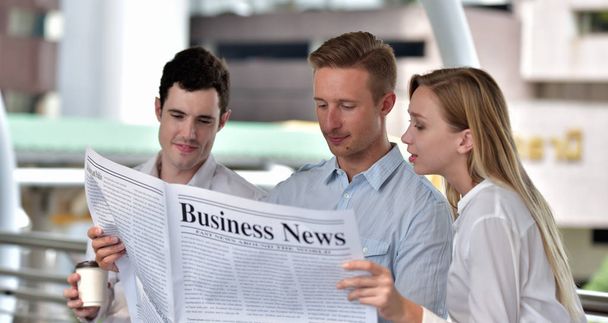 Üç iş adamı gazete okuyor ve şehir merkezinde tartışıyorlar. - Fotoğraf, Görsel
