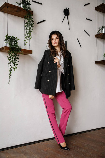 Fashion portrait of beauty brunette model wearing black jacket, white shirt and pink pants. Young beautiful woman posing in luxury apartments interior - Fotoğraf, Görsel