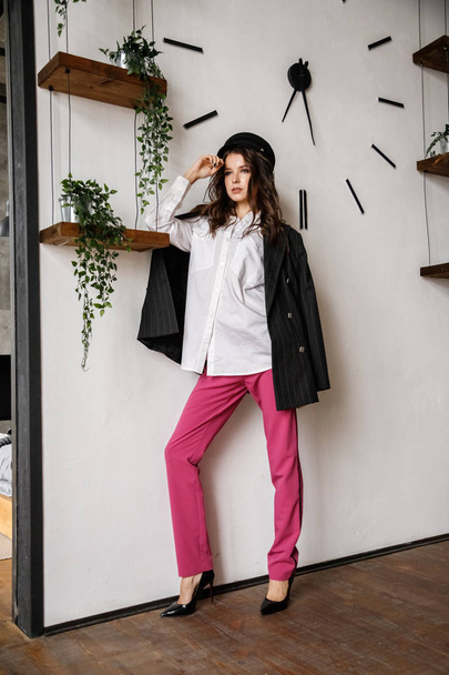 Fashion portrait of beauty brunette model wearing black jacket, white shirt and pink pants. Young beautiful woman posing in luxury apartments interior - Foto, Bild