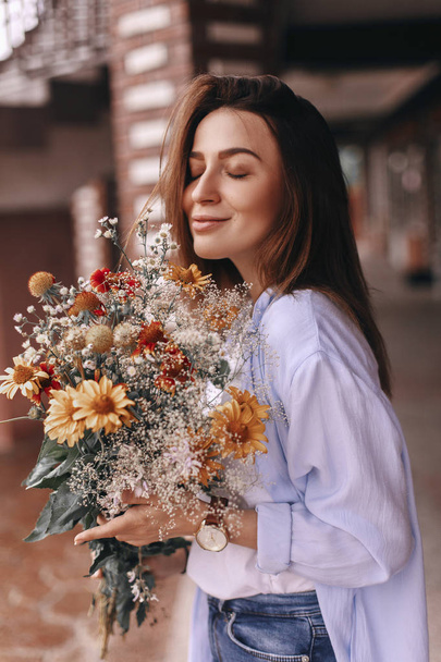 Portrait of beautiful woman which enjoying flowers. Bouquet of fields flowers - Фото, зображення