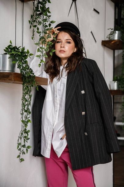 Fashion portrait of beauty brunette model wearing black jacket, white shirt and pink pants. Young beautiful woman posing in luxury apartments interior - Fotografie, Obrázek
