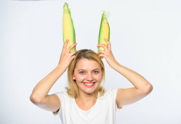 Food vegetarian and healthy organic product. Harvesting and fun. Vegetarian nutrition concept. Woman hold yellow corn cob on white background. Girl cheerful playful mood hold ripe corns as bunny ears - Fotó, kép