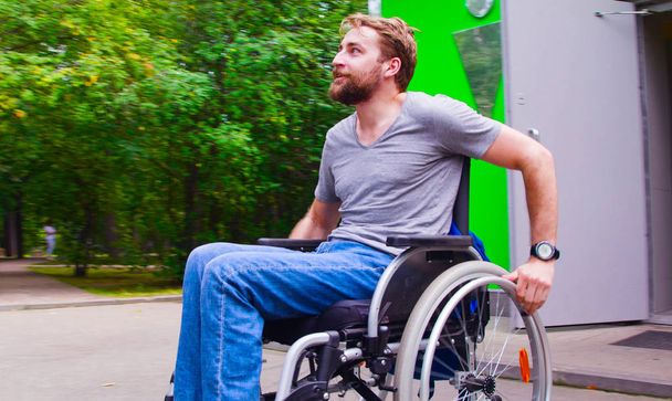 Joven hombre incapacitado caminando en el parque en silla de ruedas
 - Foto, Imagen