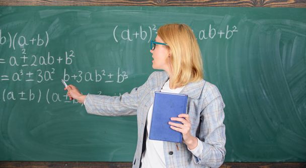 What makes great teacher. Teacher smart woman with book explain topic near chalkboard. School teacher explain things well and make subject interesting. Teaching complex multifaceted activity - Photo, Image
