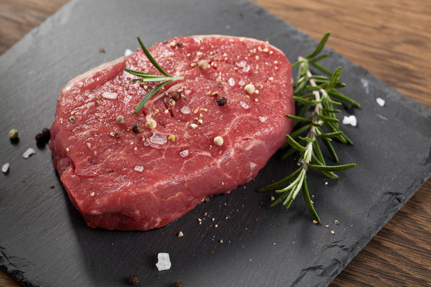 Raw beef steak on a dark wooden table. - Foto, Imagem