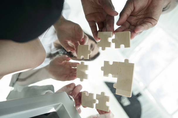 bottom view. business team folding puzzle pieces. .concept business solutions - Foto, Imagen