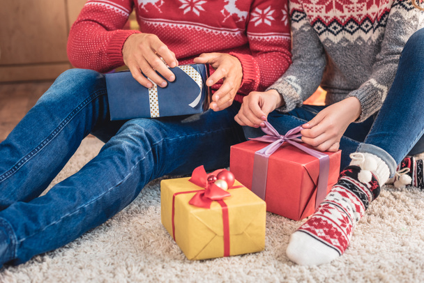 cropped image of husband and wife opening christmas presents at home - Фото, изображение
